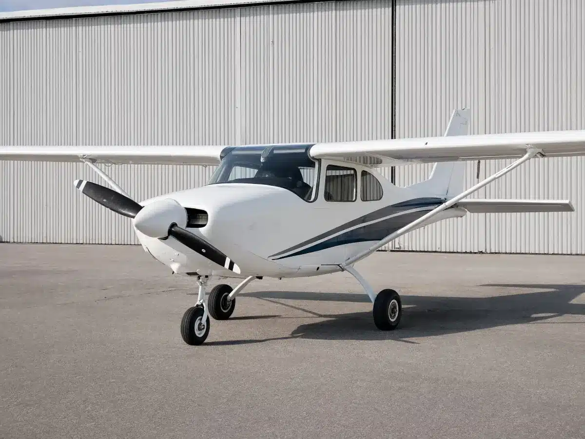 A single-engine high-wing airplane parked on a ramp